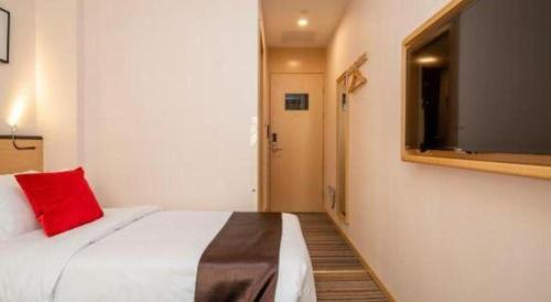a bedroom with a bed with a red pillow and a tv at Cozy Hotel Xiamen in Xiamen
