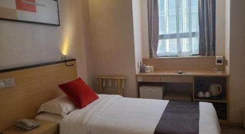 a bedroom with a bed with a red pillow and a desk at Cozy Hotel Xiamen in Xiamen