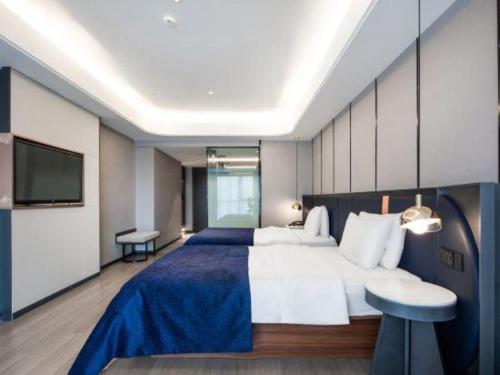 a large bedroom with a large bed and a tv at Yitel Collection Lianyungang High-speed Railway Station Suning Plaza in Lianyungang