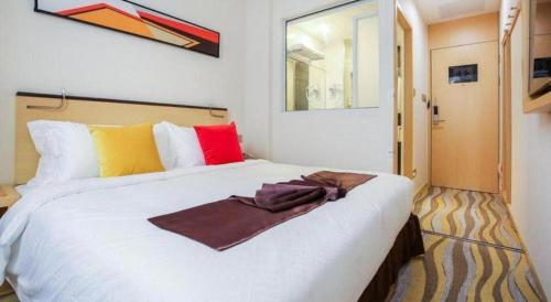 a bedroom with a large white bed with colorful pillows at Cozy Hotel Xiamen in Xiamen