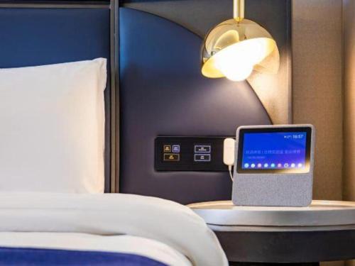 a hotel room with a bed and a laptop on a table at Yitel Collection Lianyungang High-speed Railway Station Suning Plaza in Lianyungang