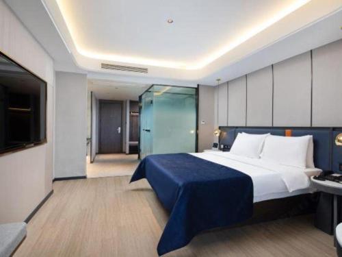 a bedroom with a large bed with a blue blanket at Yitel Collection Lianyungang High-speed Railway Station Suning Plaza in Lianyungang
