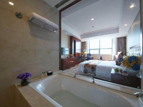 a large bathroom with a tub and a bed at New Century Hotel Putuo Zhoushan in Zhoushan