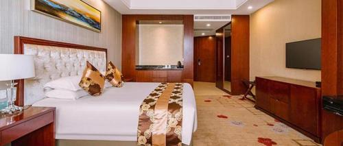 a bedroom with a large white bed and a flat screen tv at New Century Hotel Putuo Zhoushan in Zhoushan