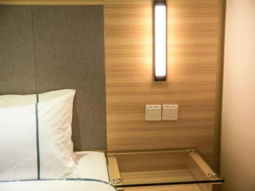 a bedroom with a bed with a light on the wall at City Comfort Inn Beihai RT-Mart High Speed Railway Station in Beihai