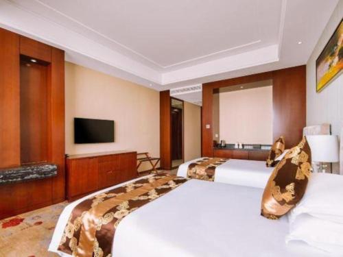 a hotel room with two beds and a flat screen tv at New Century Hotel Putuo Zhoushan in Zhoushan