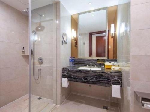 a bathroom with a shower and a sink and a mirror at New Century Hotel Putuo Zhoushan in Zhoushan