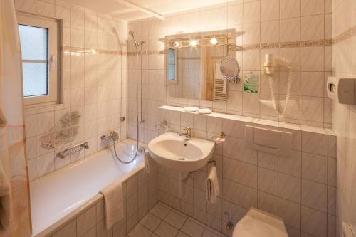 a white bathroom with a sink and a tub and a sink at Hotel Cheminee in Zermatt