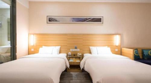 two beds in a hotel room with two beds sidx sidx sidx at City Comfort Inn Wuhan High Speed Railway Station in Wuhan