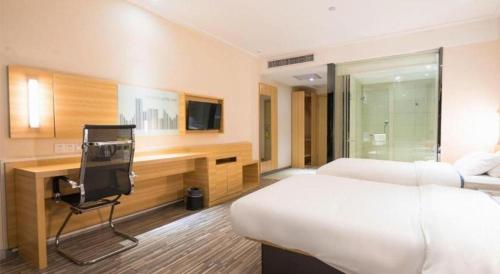 a hotel room with two beds and a desk with a television at City Comfort Inn Wuhan High Speed Railway Station in Wuhan