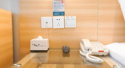 a room with a phone on a table with a bed at City Comfort Inn Wuhan High Speed Railway Station in Wuhan