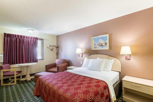 a hotel room with a bed and a chair at Americas Best Value Inn Beatrice in Beatrice
