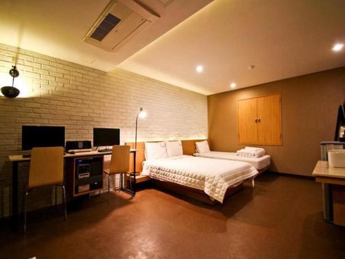 a bedroom with a bed and a desk with a computer at Comma Hotel in Busan