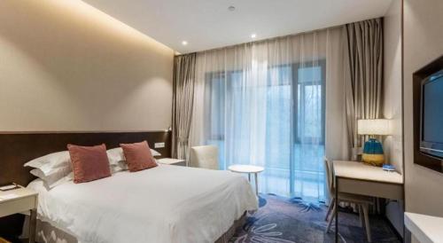 a hotel room with a bed and a desk and a television at International Conference Hotel Nanjing in Nanjing