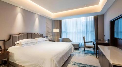 a bedroom with a large white bed and a bathroom at International Conference Hotel Nanjing in Nanjing