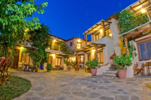 a house with a courtyard at night at Alkifron Hotel in Kala Nera