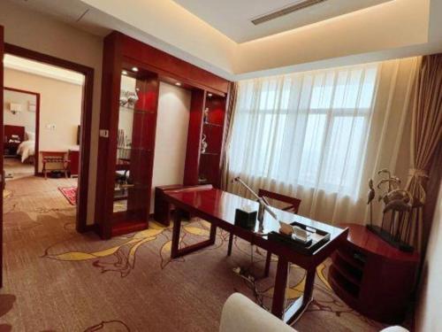 a living room with a desk and a large window at Qingdao Blue Horizon Hotel Licang in Qingdao