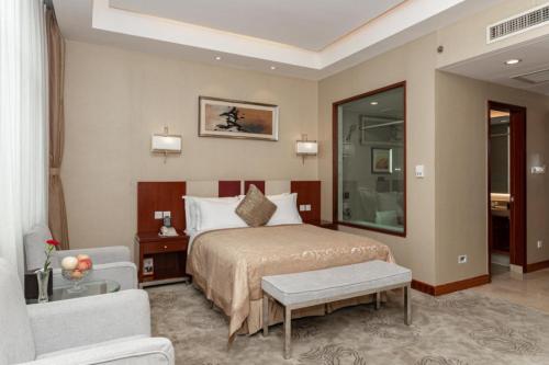 a bedroom with a bed and a chair and a couch at Qingdao Blue Horizon Hotel Licang in Qingdao