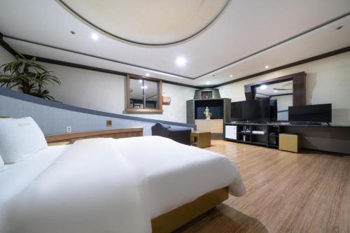 a bedroom with a large white bed and a living room at Hotel Head-One in Uijeongbu