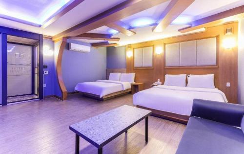 a hotel room with two beds and a table at Hotel Head-One in Uijeongbu
