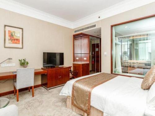 a bedroom with a bed and a desk and a television at Qingdao Blue Horizon Hotel Licang in Qingdao