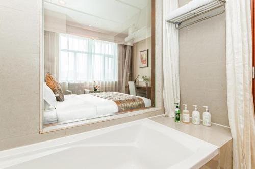 a bedroom with a bed and a large mirror at Qingdao Blue Horizon Hotel Licang in Qingdao