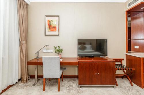 a hotel room with a desk with a tv and a computer at Qingdao Blue Horizon Hotel Licang in Qingdao