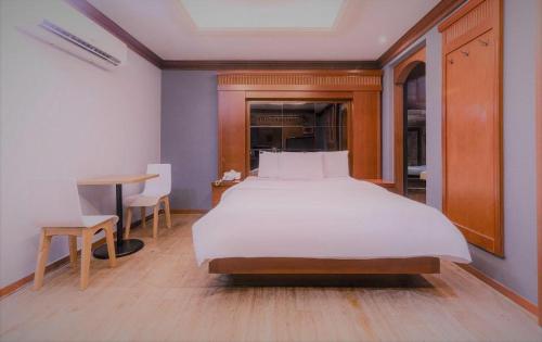 a bedroom with a large white bed and a table at Hotel Head-One in Uijeongbu