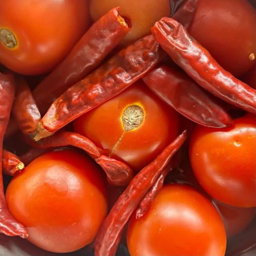 a pile of tomatoes and peppers in a bowl at Joy Source Resort in Kathmandu