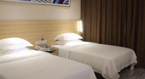 two beds in a hotel room with white sheets at City Comfort Inn Foshan Shunde Daliang Qinghui Garden Xinsong in Shunde