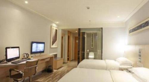 a bedroom with a bed and a desk with a computer at City Comfort Inn Foshan Shunde Daliang Qinghui Garden Xinsong in Shunde