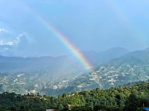 a rainbow in the sky over a mountain at Joy Source Resort in Kathmandu