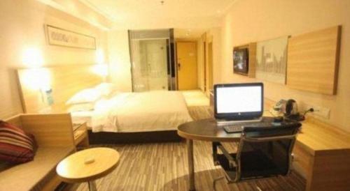 a hotel room with a bed and a desk with a laptop at City Comfort Inn Foshan Shunde Daliang Qinghui Garden Xinsong in Shunde