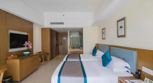 a large bedroom with a large bed with blue pillows at Da Peng Zhongzhou Hotel in Haikou
