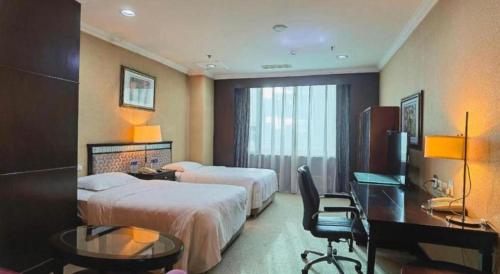 a hotel room with two beds and a desk at Changchun Zhuozhan Days Hotel in Changchun