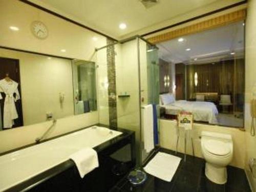 a bathroom with a tub and a toilet and a bed at Changchun Zhuozhan Days Hotel in Changchun
