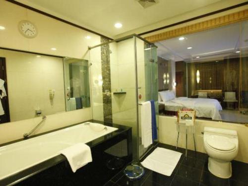 a bathroom with a tub and a toilet and a bed at Changchun Zhuozhan Days Hotel in Changchun