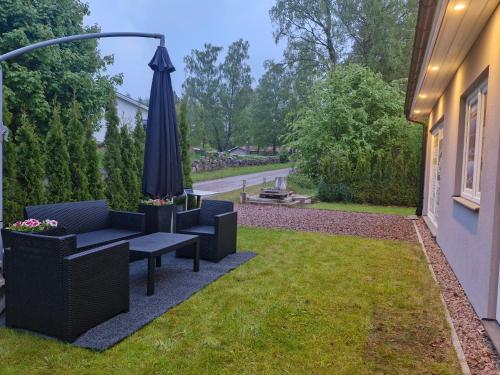 a patio with an umbrella and chairs and a lawn at HOLIDAY NEST Family Apart Guest House 26m2 - Mysigt studio för 4 pers in Höör
