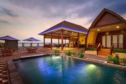 a house with a swimming pool in front of a house at Bayview Beach Resort East Lombok in Labuan Lombok