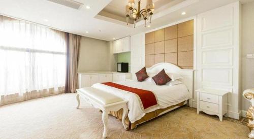 a bedroom with a large white bed and a chandelier at New century Manju Select Hotel Hongqiao Hub National Exhibition Center in Shanghai