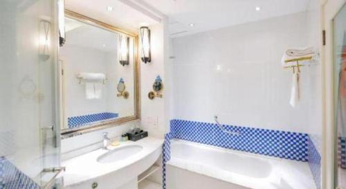 a bathroom with a tub and a sink and a mirror at New century Manju Select Hotel Hongqiao Hub National Exhibition Center in Shanghai