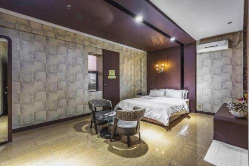 a bedroom with a bed and chairs in a room at Qingdao Hengbo Hotel in Qingdao