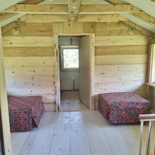 an attic room with two beds and a window at Planinska Priča in Ljenobud