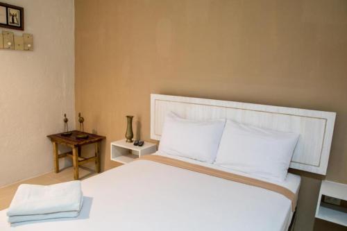 a bedroom with a large white bed and a table at Hotel Avenija in Olongapo