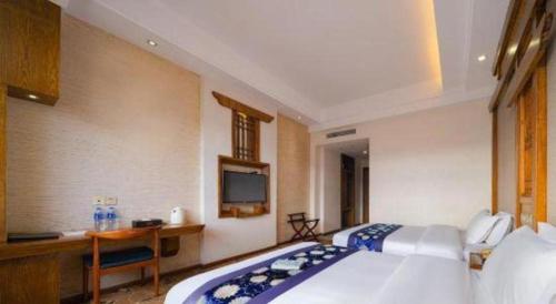 a bedroom with a bed and a desk and a television at Zhangjiajie Xiangfu International Hot Springs Hotel in Zhangjiajie