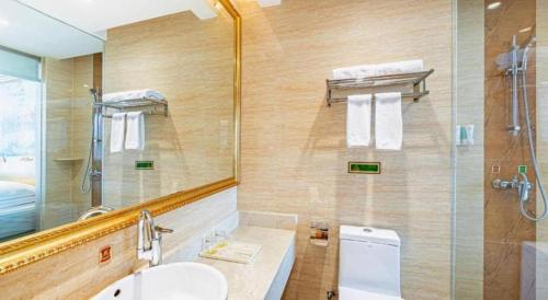 a bathroom with a toilet and a sink and a mirror at Vienna Classic Hotel Qingdao Huangdao in Huangdao