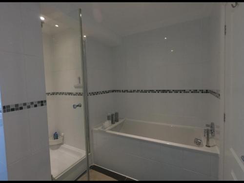 a white bathroom with a tub and a shower at King size room with own bathroom & livingroom in a luxury home, free WiFi, HOMESTAY in West Byfleet