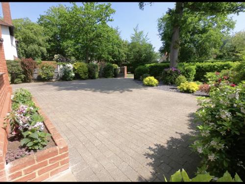 a garden with a brick driveway and flowers at King size room with own bathroom & livingroom in a luxury home, free WiFi, HOMESTAY in West Byfleet