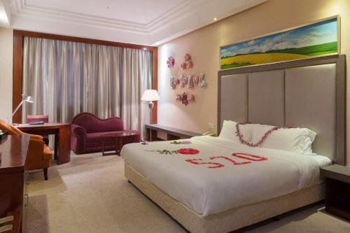 a hotel room with a large white bed and a chair at Jie Hao Royal Hotel in Shenzhen
