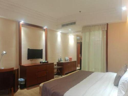 a hotel room with a bed and a flat screen tv at Jie Hao Royal Hotel in Shenzhen